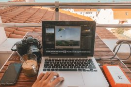 person holding MacBook Pro besides orange power bank